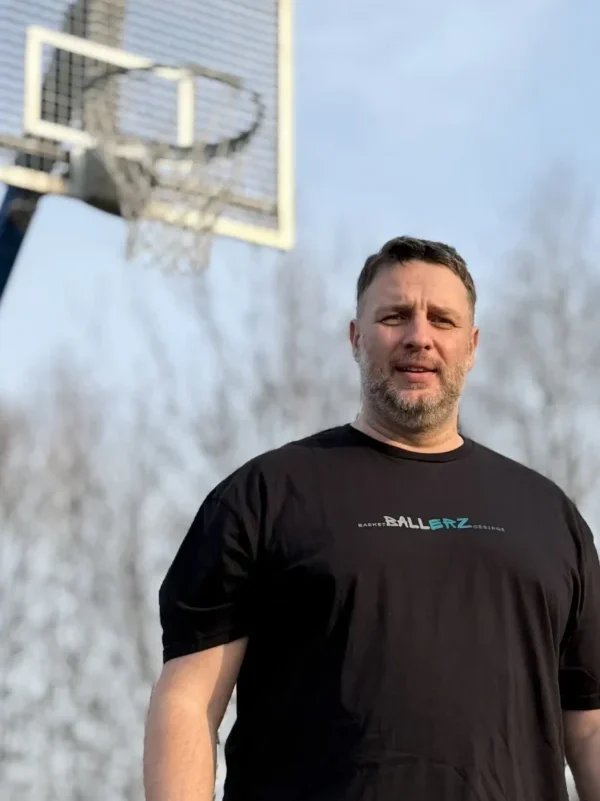 Bild von Andreas Pult bekleidet in einem schwarzen T-Shirt mit der Aufschrift Ballerz. Im Hintergrund ist ein Basketballkorb zu sehen