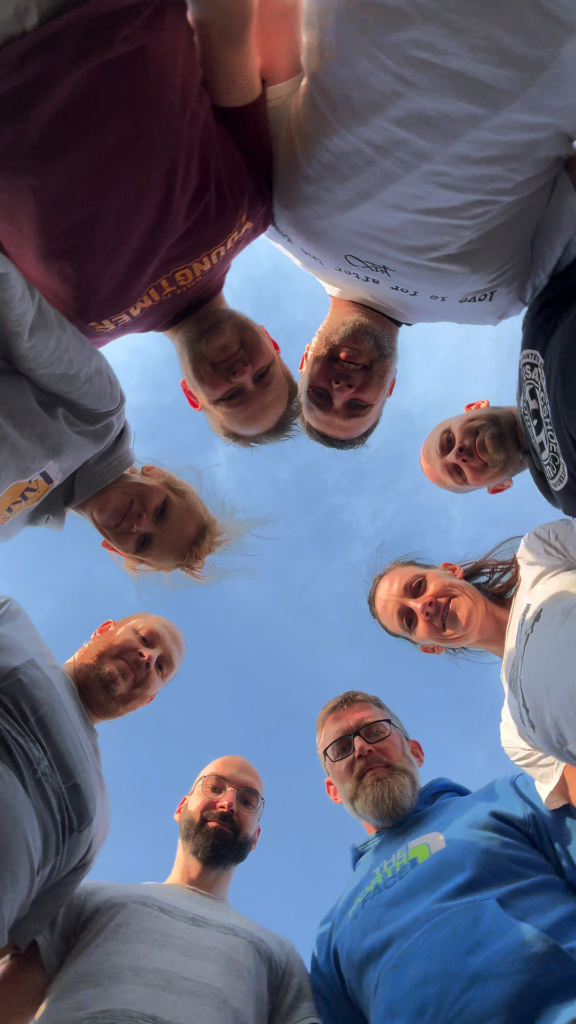 Orgateam der Ballers steht im Kreis und schaut nach unten in die Kamera