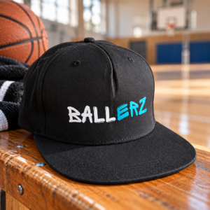 Schwarzes Ballerz Basecap mit Ballerz Schriftzg auf der Vorderseite auf einer Bank in einer Turnhalle liegend