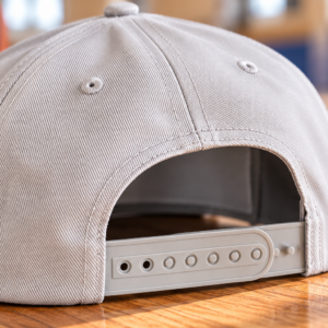 Snapback Detail graues Cap Detailaufnahme des Verschlusses eines grauen Basecaps. Snapback Verschluss